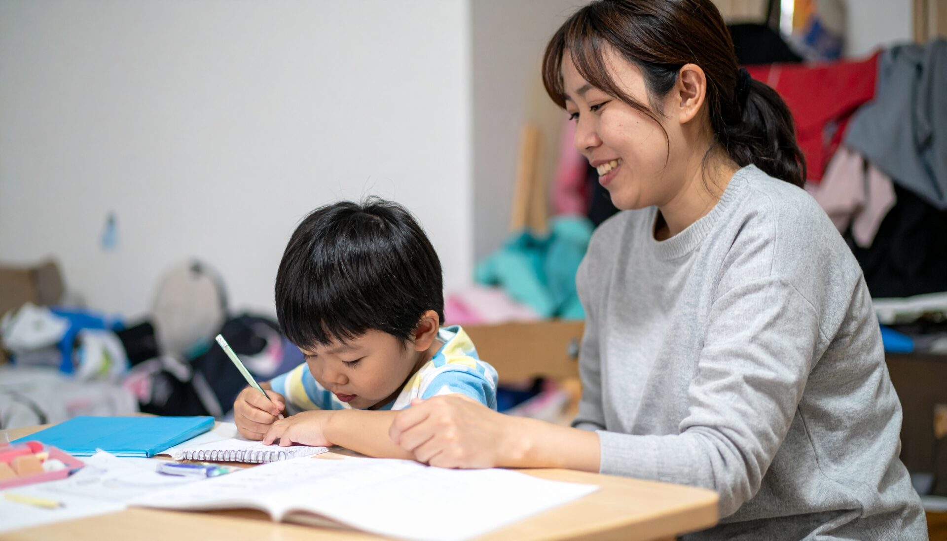 部屋は散らかっているが、子どもが一人で学習に集中している姿を見て、少しだけほっとしている親の微笑