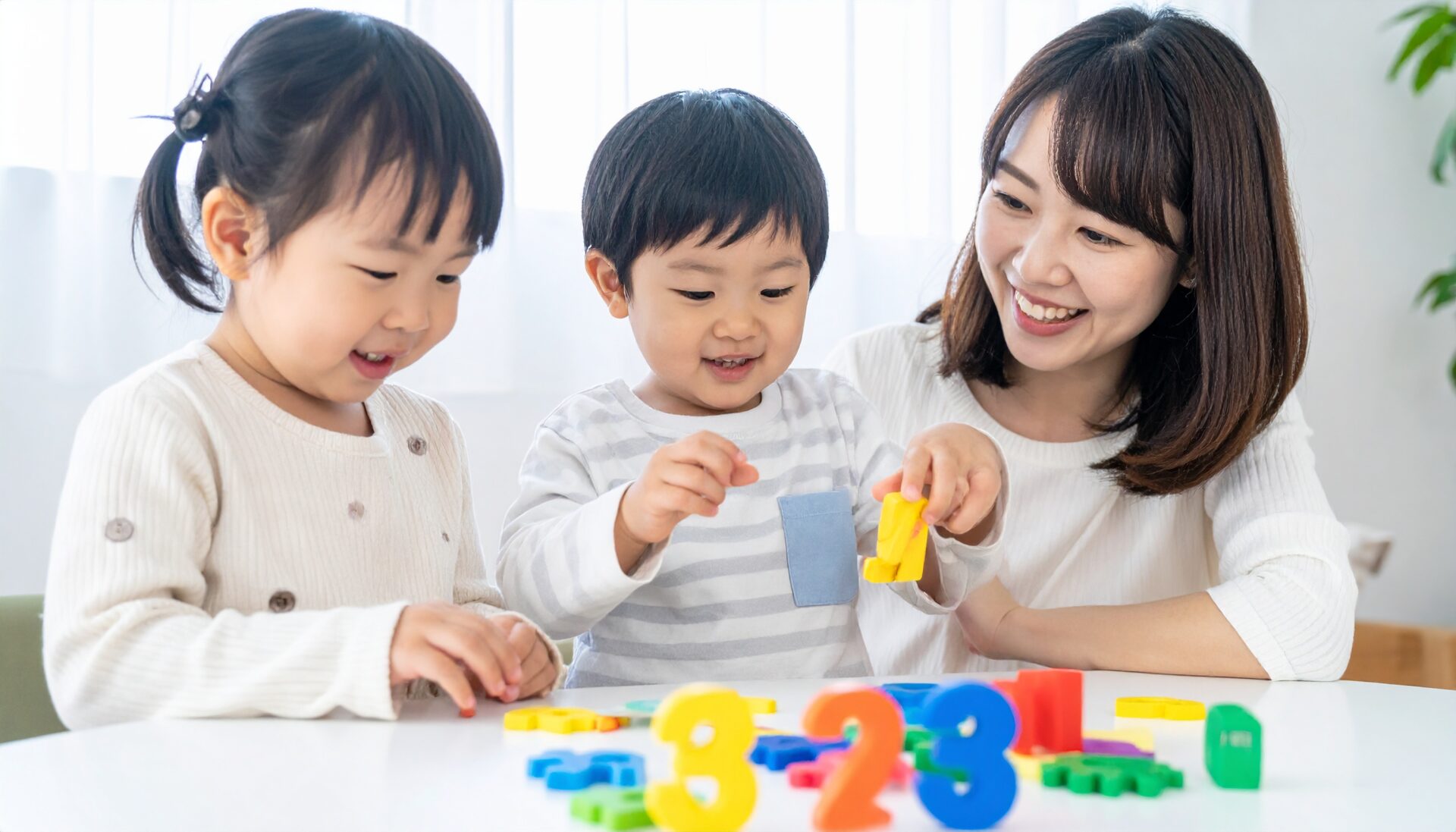日本人の幼児が、カラフルで楽しげな数字ブロックや数字パズル、お金遊びや数のカードゲームなどを使って、“遊びながら自然に数字を覚えている”様子。笑顔で『3はどれかな?』と探したり、親と一緒に楽しそうに数を数えている場面。明るく温かみのある家庭の室内環境。